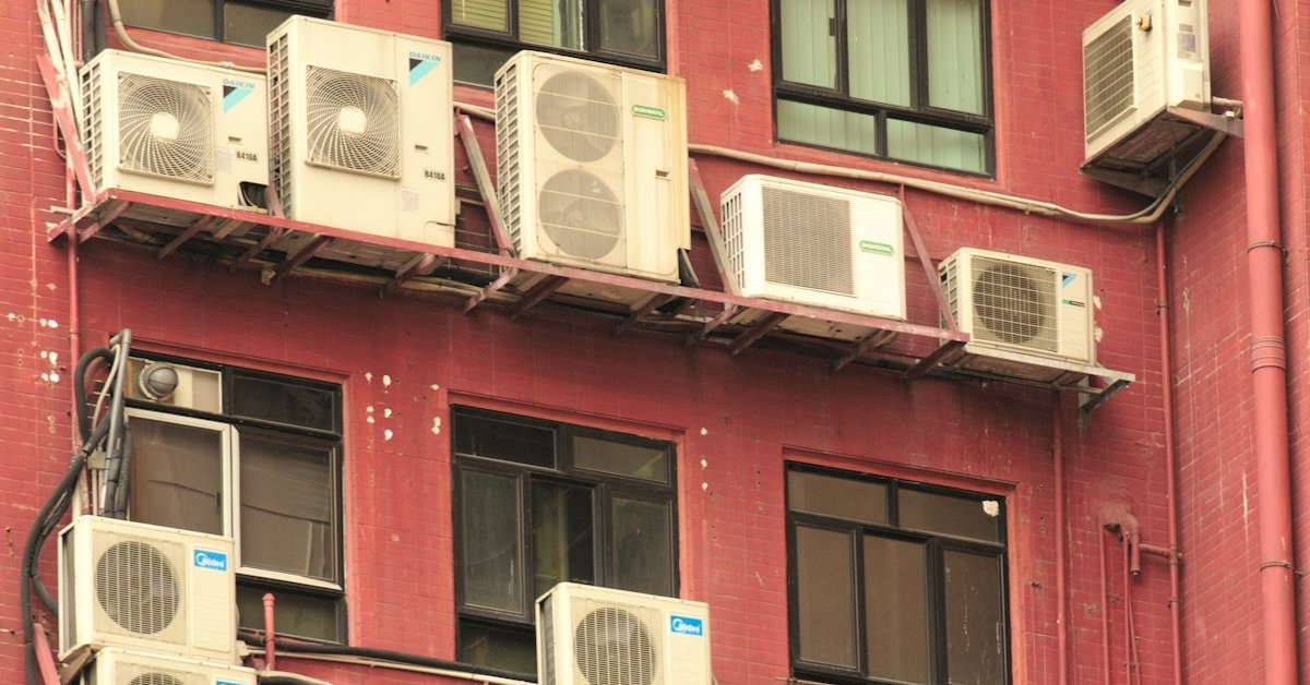 Row of outdoor AC condenser units mounted on a building exterior