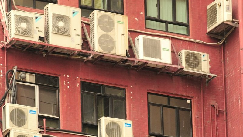 Row of outdoor AC condenser units mounted on a building exterior